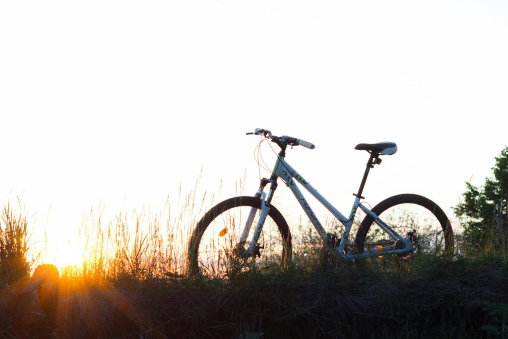 A bicycle silhouetted against a sunset, captured in a serene natural setting.