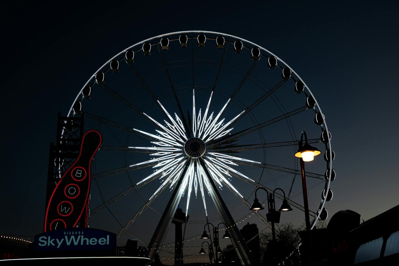 Stunning view of the illuminated SkyWheel in Niagara Falls at night, showcasing vibrant lights and fairground atmosphere.