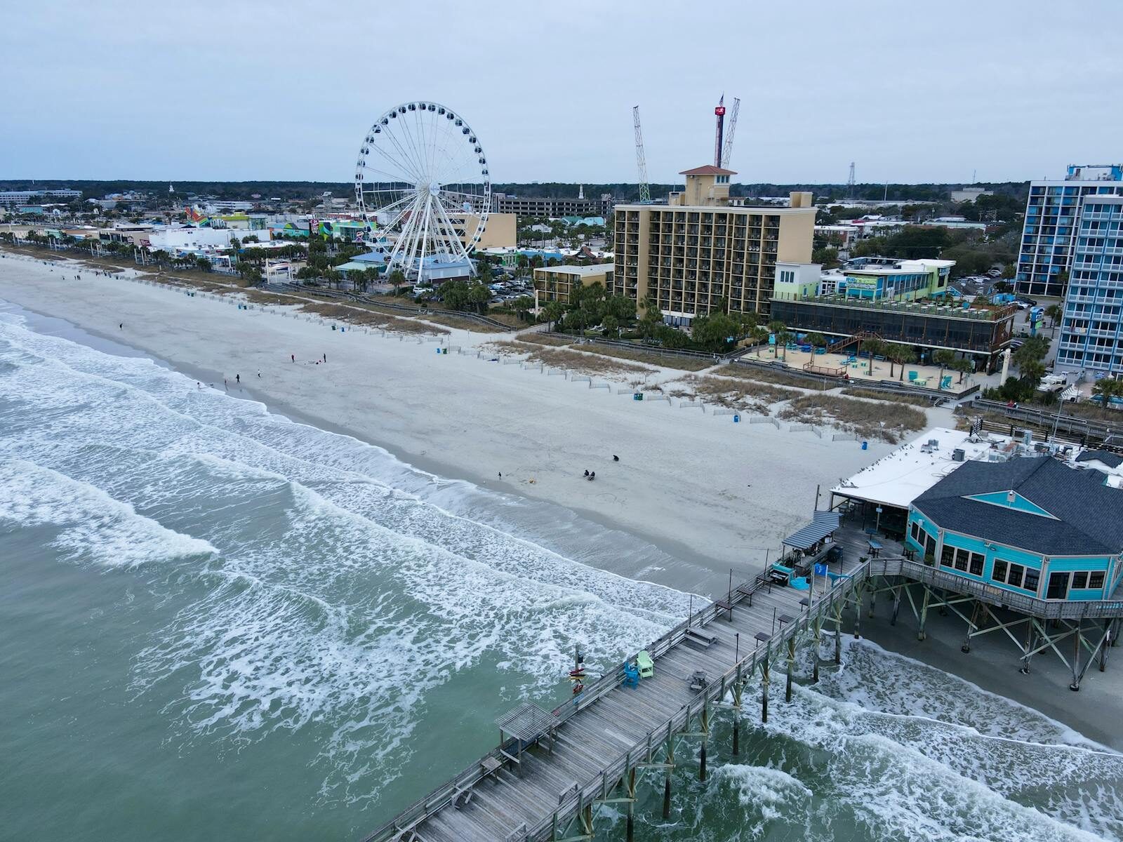 Aerial shot of Myrtle Beach with iconic pier and ferris wheel, capturing coastal beauty.