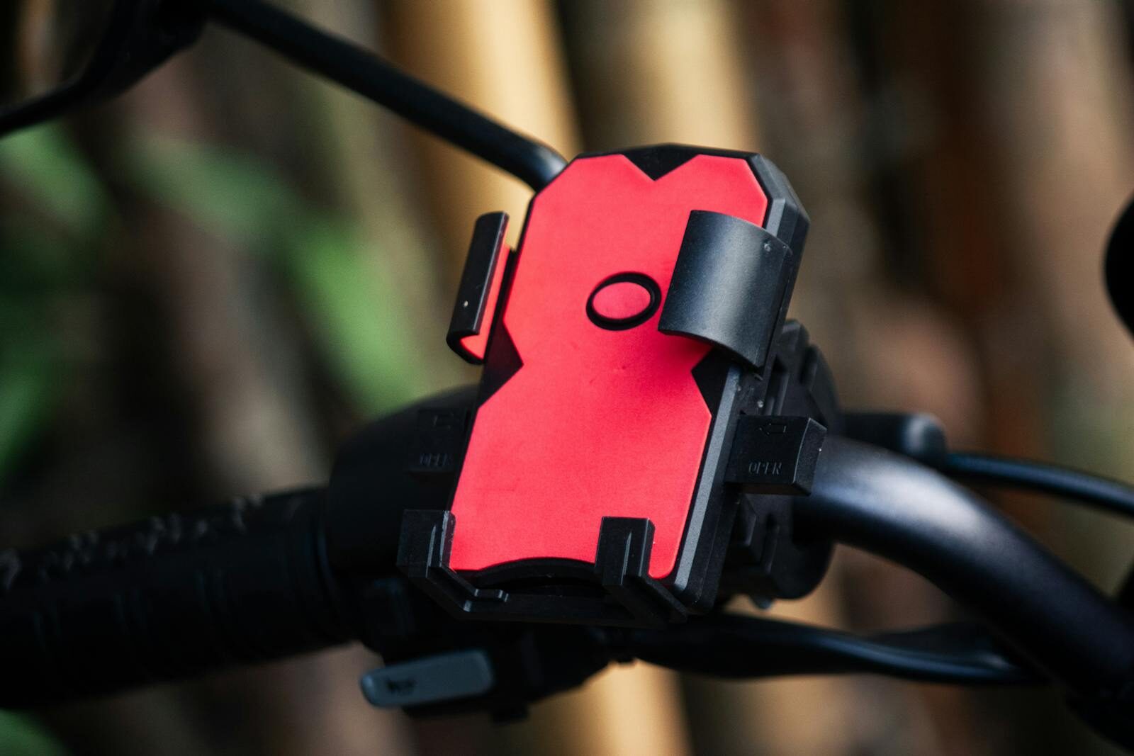 Photo by HARIPRASAD CE Close-up of a red phone holder mounted on a bicycle handlebar outdoors.