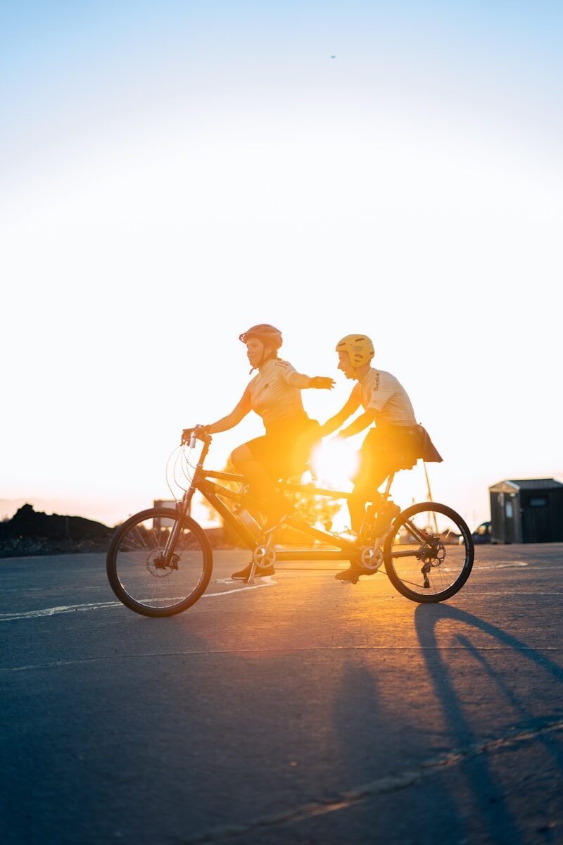 Couple rides a tandem bicycle at sunset.