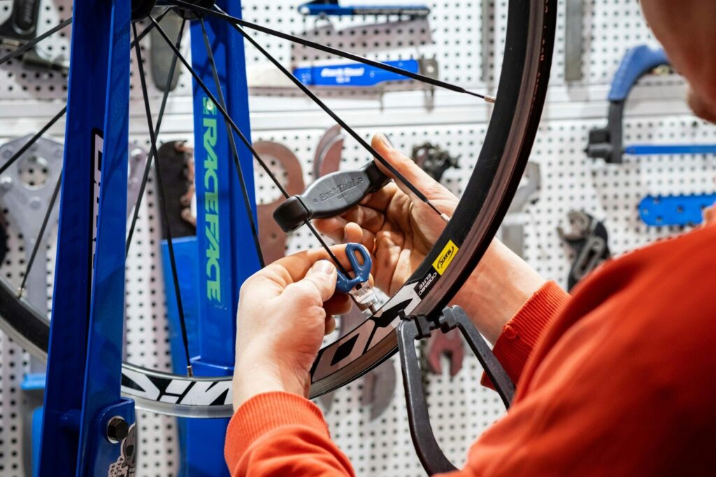 a man working on a bicycle wheel in a shop