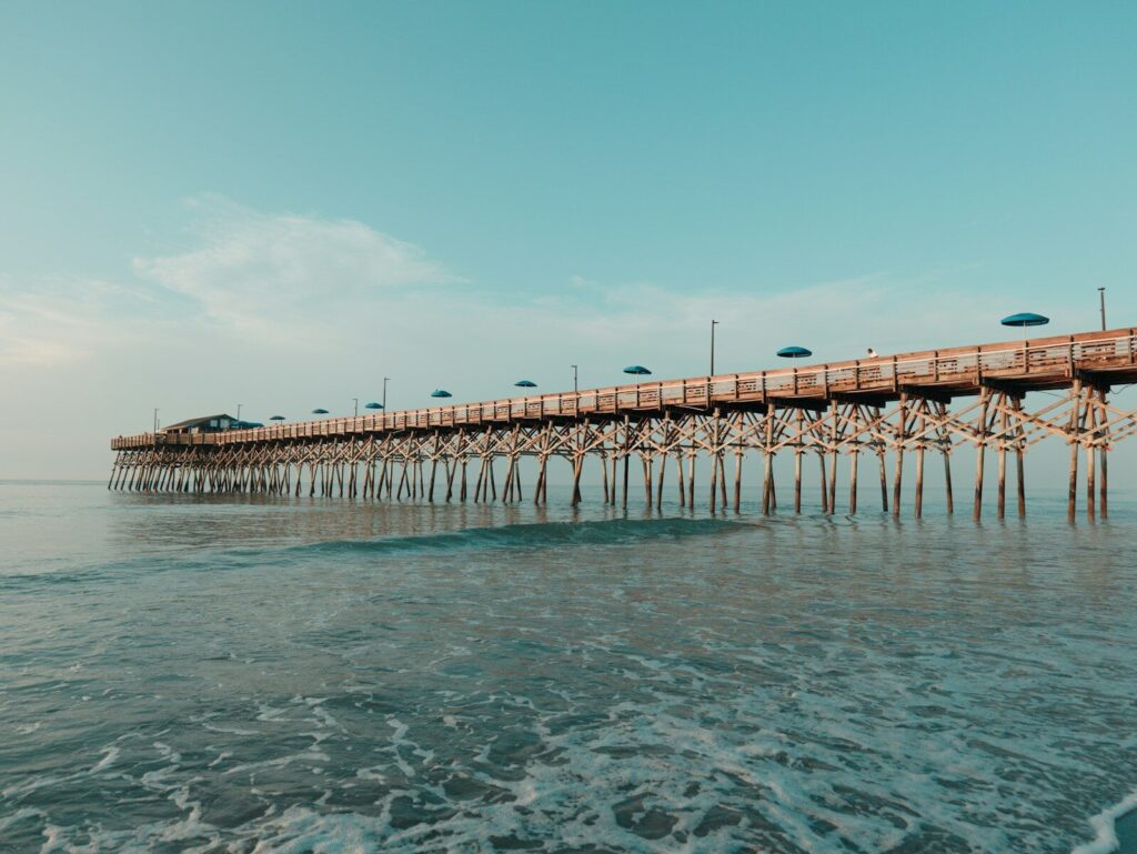 A long pier stretches over calm ocean waters.