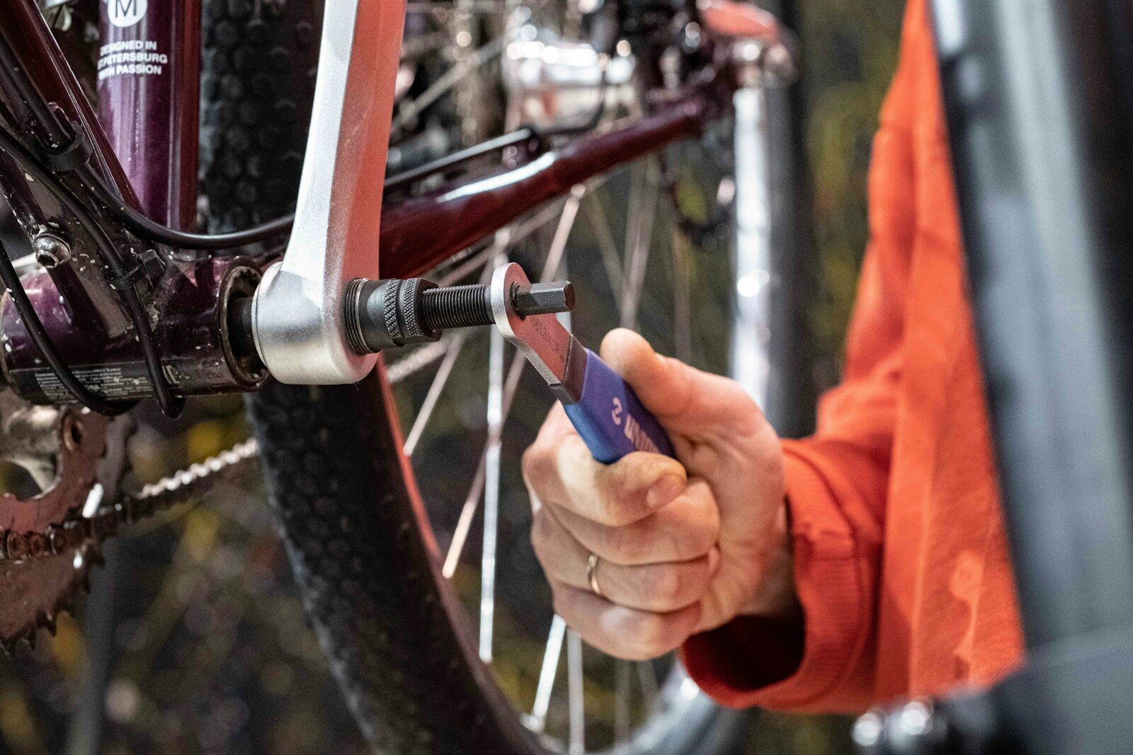 Photo by Anton Savinov a person holding a wrench in front of a bike