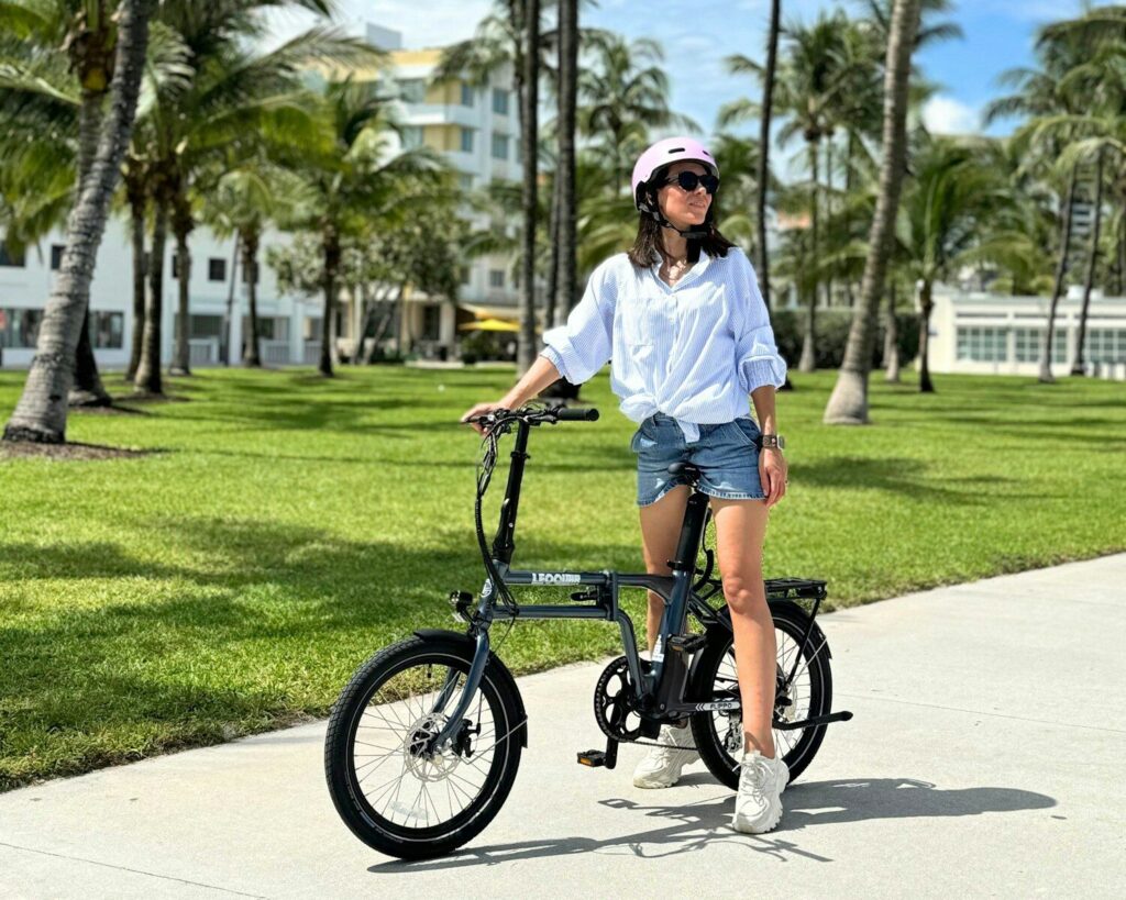A woman riding a bike down a sidewalk